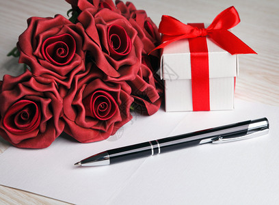 带笔红玫瑰和白色礼品图片