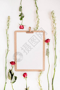 红玫瑰和白花框白色背景上贴有剪贴板平图片