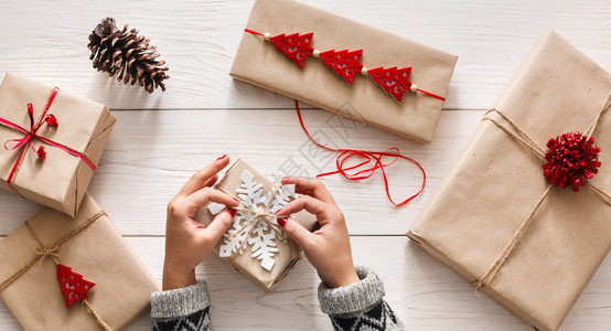 创意爱好女人的手用麻绳把圣诞假期手工制作的礼物包在牛皮纸上在圣诞礼品盒上做弓背景图片