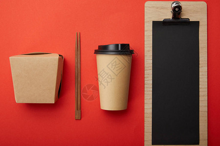 红色表面上排列的可支配咖啡杯筷子圆框和空白菜背景图片
