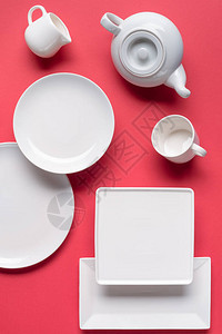 红色背景中的白色陶器盘和茶具图片