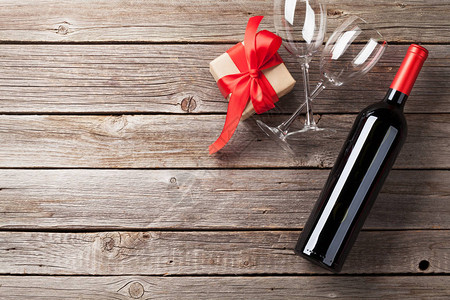 情人节贺卡与红酒和木桌上的礼品盒图片
