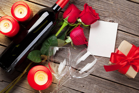 情人节贺卡木桌上有红玫瑰花酒和蜡烛图片