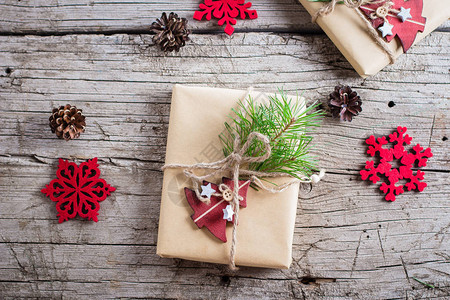节日圣诞礼盒圣诞礼物与冷杉树枝和木桌背景上的红色木树玩具装饰顶视图片