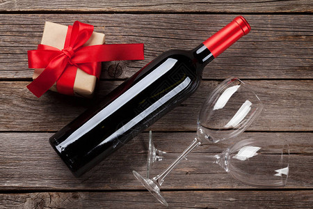 木桌上的红酒瓶和礼品盒情人节贺卡顶视图背景图片