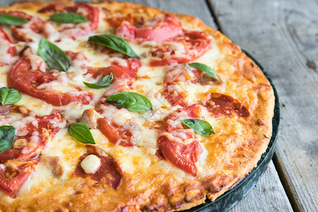鲜热自制辣椒披萨在生锈的木制桌上配番茄奶酪和烤肉的披萨图片