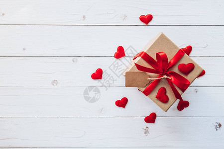 顶部上面礼物盒和红丝带和红心用于餐桌木板上的情人节图片