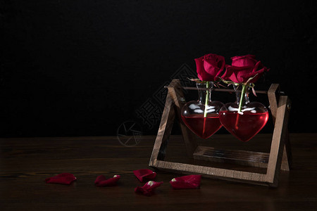 两朵红玫瑰在心胸中在木架上形成花瓶高清图片
