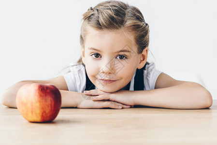 坐在桌边的小女孩和红苹果坐在一起图片