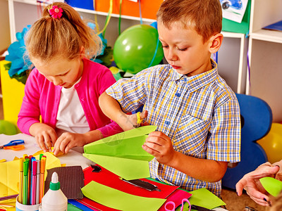 一群孩子在幼儿园的桌子上做纸折图片