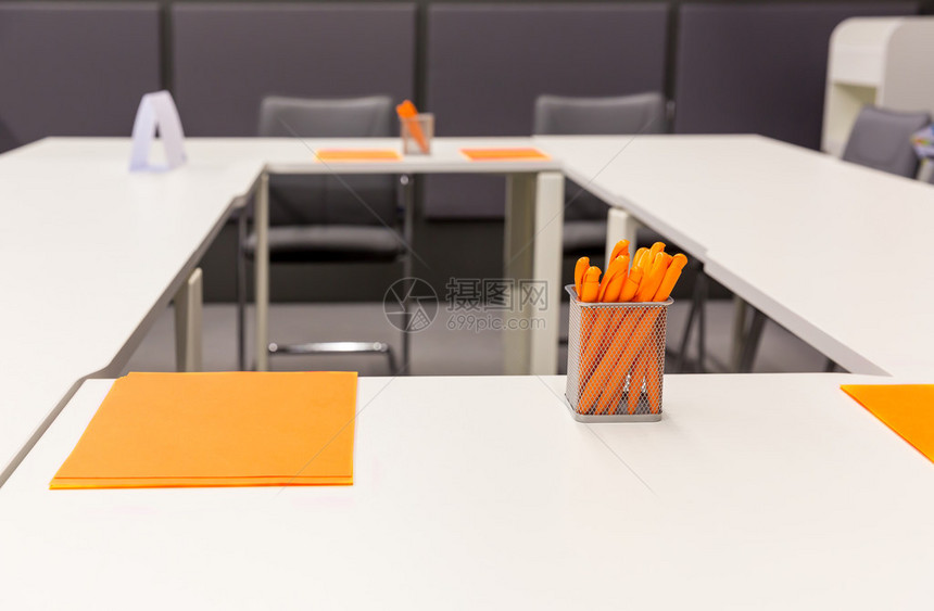 桌上有橙笔和纸的现代图片
