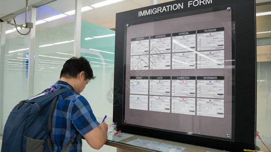 亚洲男子旅客在机场海关服务区填写移民表格图片