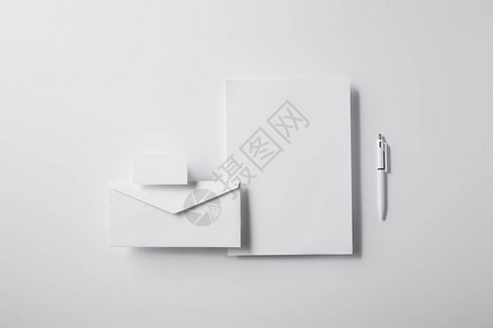 以笔空白纸和名片挂在用于模拟的白色桌面上的商务卡为包装信封图片