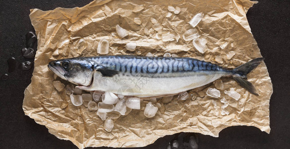 黑背景的手工艺纸上的冰上新鲜竹鱼海产食品餐厅有机烹饪材料顶视图片