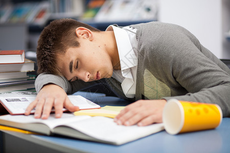 疲倦的学生睡在图书馆的课桌前图片