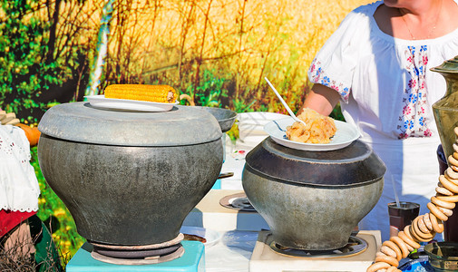 桌上是煮铁锅煮熟的玉米炖土豆百吉饼茶杯图片