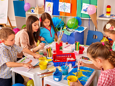 幼稚园桌边有女教师儿童在纸上绘画图片