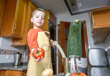 用围裙烹煮大青菜和其他蔬菜的可爱儿童厨师图片