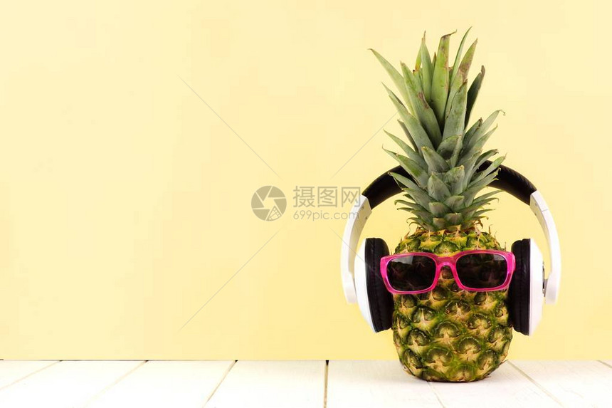 在黄色背景下戴墨镜和耳机的歇斯底里菠萝图片