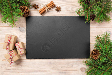 圣诞装饰木桌上的石板盘木制背景上的黑色石板复制空图片