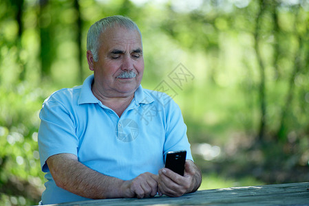 长年男子在手机上看短片或短信时微笑图片
