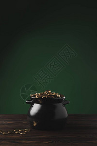 绿色的木桌上的黑锅金质硬币图片