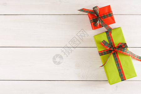 彩色点状包装纸上的礼品盒的顶部视图用方格缎带绑在白色质朴的桌子上图片