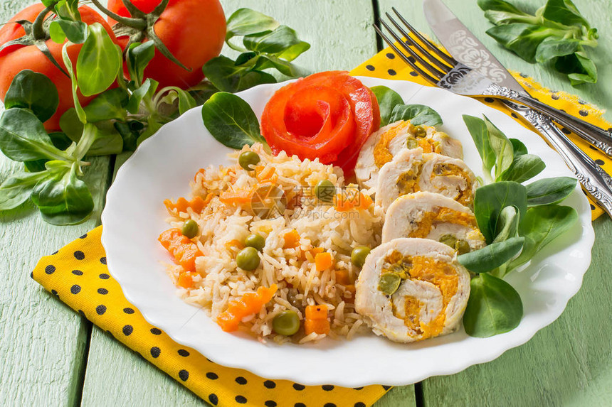 酿鸡胸肉卷配胡萝卜和青豆切片配上辣米饭和蔬菜绿色的木制背景图片