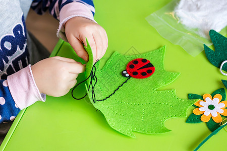 孩子制作绿叶和红色瓢虫的毛毡绒玩具儿童DIY活动特写儿图片