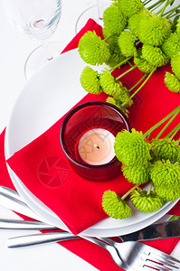 配有红色和绿色的菊花玻璃杯蜡烛餐巾纸和餐图片