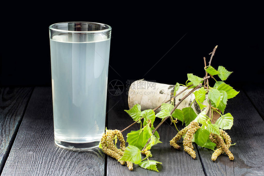 春季有用的维生素饮料玻璃杯中的新鲜冷桦树汁和深色背景中的桦树枝健康和维生图片