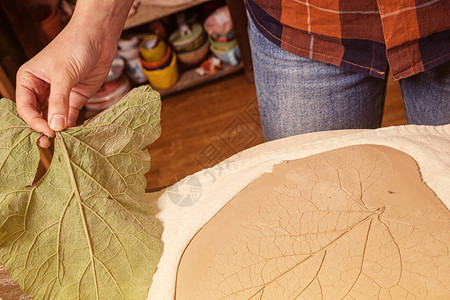 一位身穿格子衬衫的女陶工的特写是用一块砖状的粘土大平板制成图片