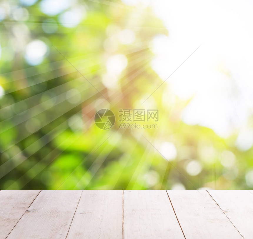 抽象模糊的绿叶和阳光下的白色木桌图片