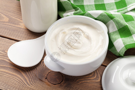 碗里的酸奶油和木桌上的奶瓶图片