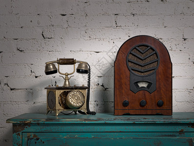 复古旧木制收音机和旧电话机的静物画在绿色复古木制彩色桌子上图片