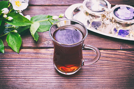 黑茶在一个玻璃透明杯中手柄在棕色木头背景上顶视面图片