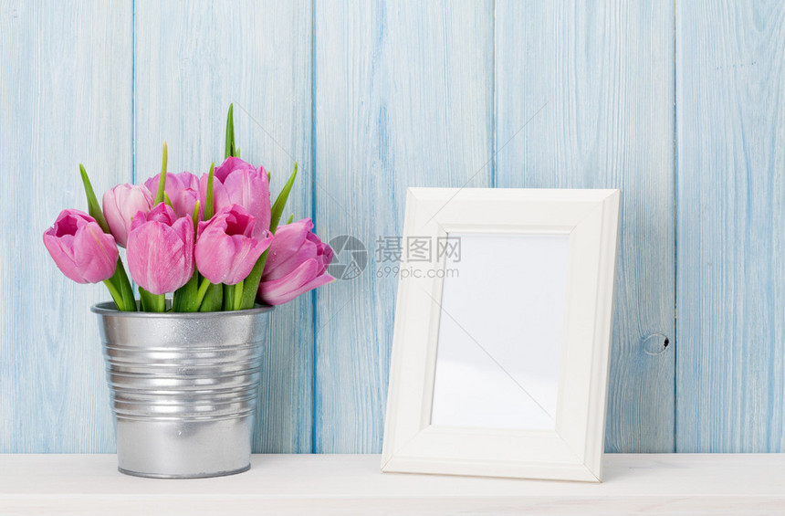 粉红新郁金香花束和空白照片框在木墙前架图片