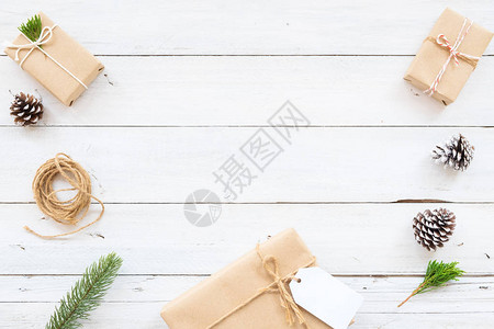 圣诞节背景与手工制作的礼物盒和白色木板上的乡村装饰具有边框和复制空间设计的创意平面布局背景图片