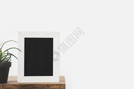 框架中的黑板和白色桌子上的植物图片