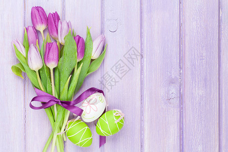 紫色郁金香花束和圆形鸡蛋放在木桌上图片