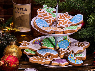 分层饼干架上的圣诞姜饼和白瓶酒木桌和圣诞树圣图片