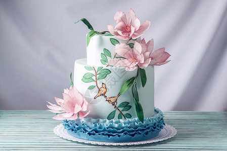 一个美丽的家庭婚礼三层蛋糕上面装饰着粉红色花朵和树枝还有绿色的叶子图片