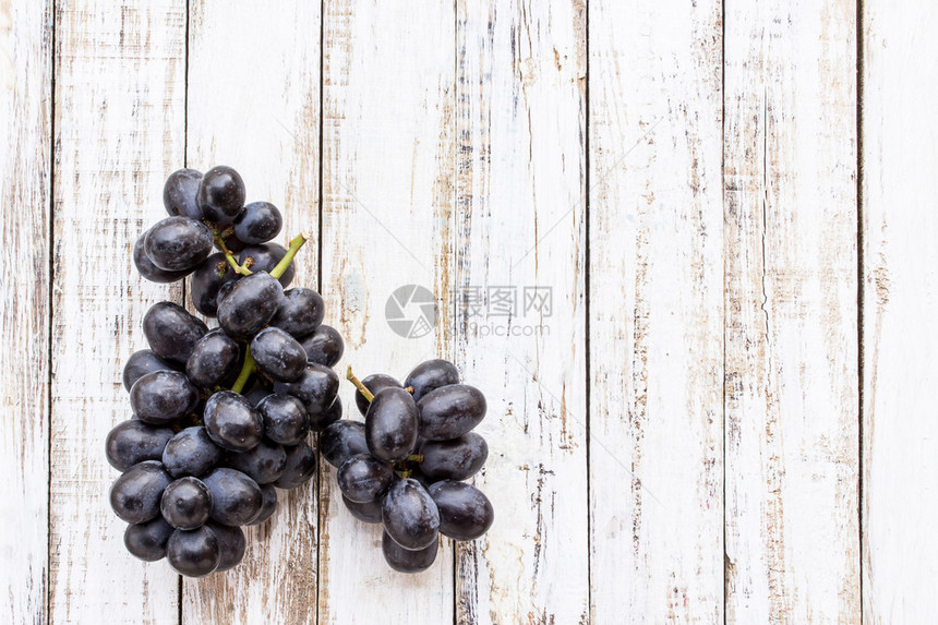 白木桌背景上的葡萄图片