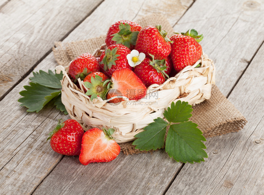 木桌背景上篮子里的新鲜草莓图片