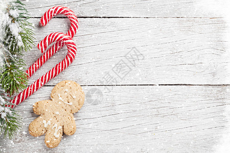圣诞糖果甘蔗姜饼人和木制桌上的雪花壁树带有空图片