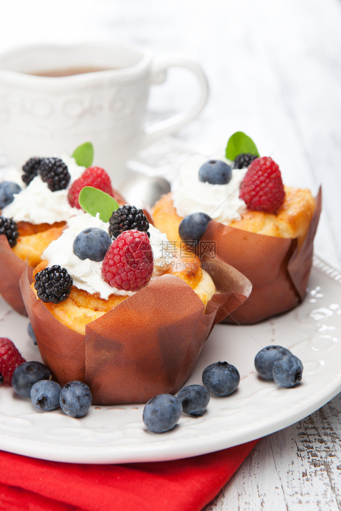 新鲜香草纸杯蛋糕配覆盆子蓝莓和薄荷在白色木质背景上图片