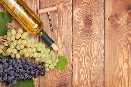 白葡萄酒瓶和木桌背景的一串葡萄图片