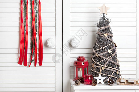 绿色红梦捕捉者红烛台和白色门背景的木圣诞树图片