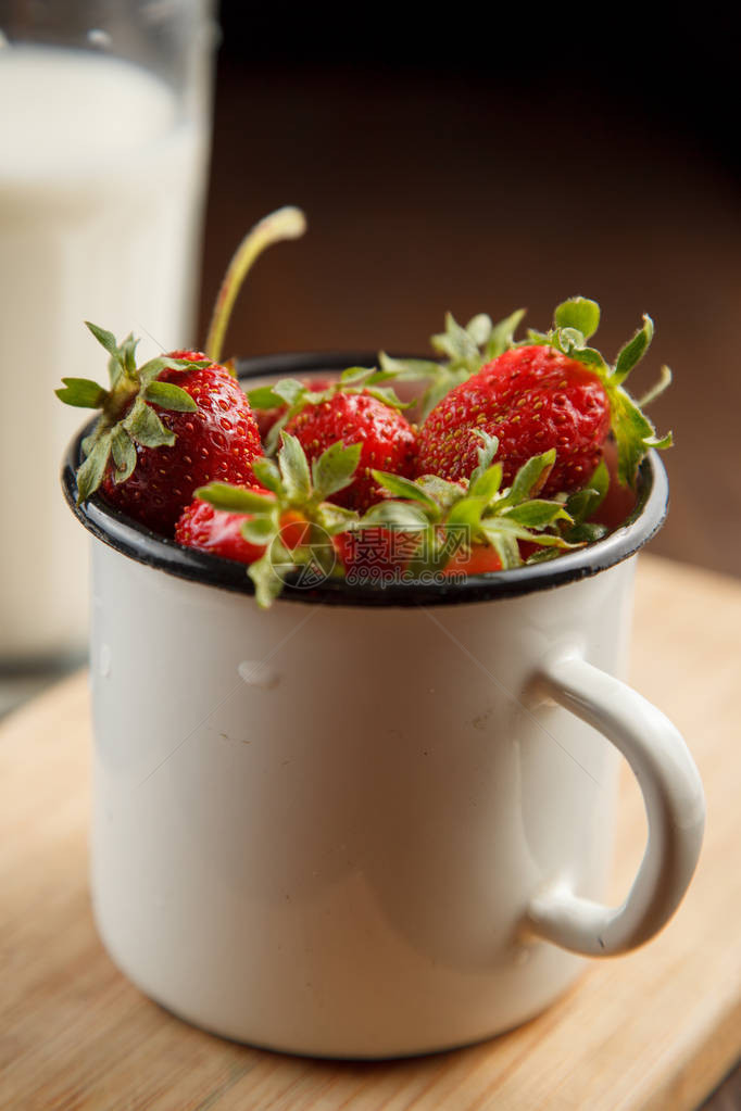 在搪瓷杯中装满成熟草莓配上一杯牛奶图片