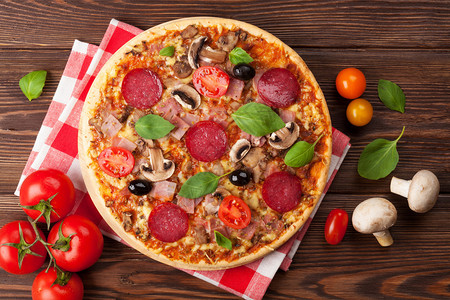 意大利披萨木制桌上有辣椒西红柿图片